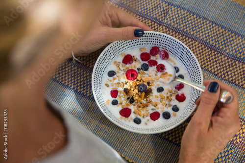 Over shoulder view of woman eating cereal and berry breakfast photo