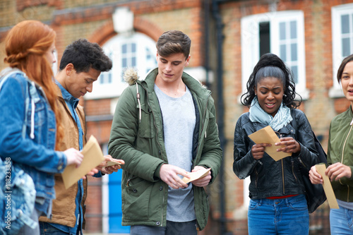 Young adult college students opening exam results on campus