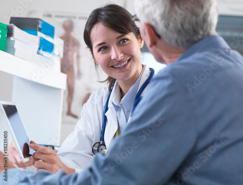 Doctor sharing health information on digital tablet with patient in clinic photo