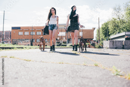 Two young women walking pit bull dog in urban housing estate