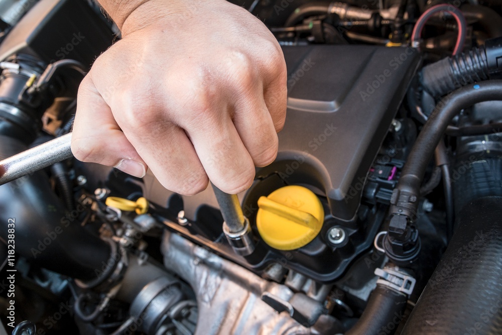 Hand repairing a modern car engine with a wrench Hand repairing a modern car engine with a wrench