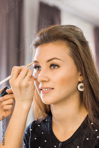 Make-up artist doing makeup for young woman