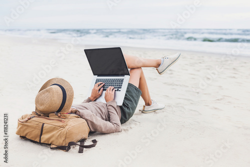 Young woman using laptop computer on a beach. Freelance work, e-learning, social distancing, distance work, connection concept