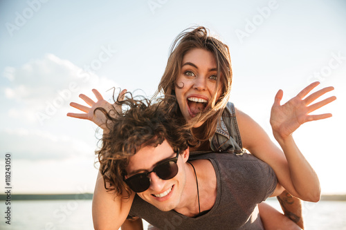 Young happy smiling couple in love piggyback at the beach photo