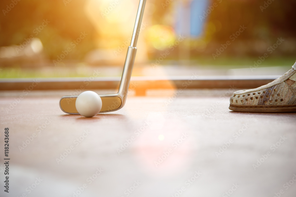 Fototapeta premium In der Abendsonne auf der Minigolfbahn. Schläger und Ball sind bereit zum einputten.