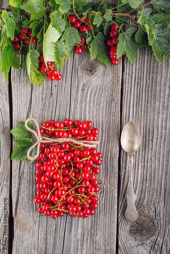 Fototapeta Naklejka Na Ścianę i Meble -  red currants like vial with twine and metal spoon and jam on wooden background, creative idea for healthy lifestyle, raw food