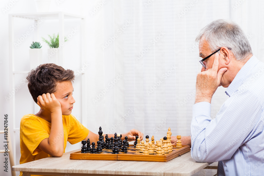 Grandfather and grandson are playing chess at home. Grandfather and grandson are playing chess at home.