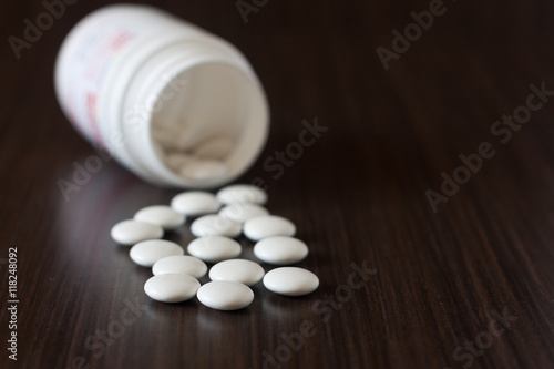 Pills from a jar on a dark background