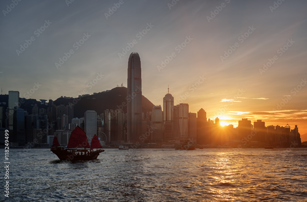 The Hong Kong Island skyline at sunset. Sailing ship in bay