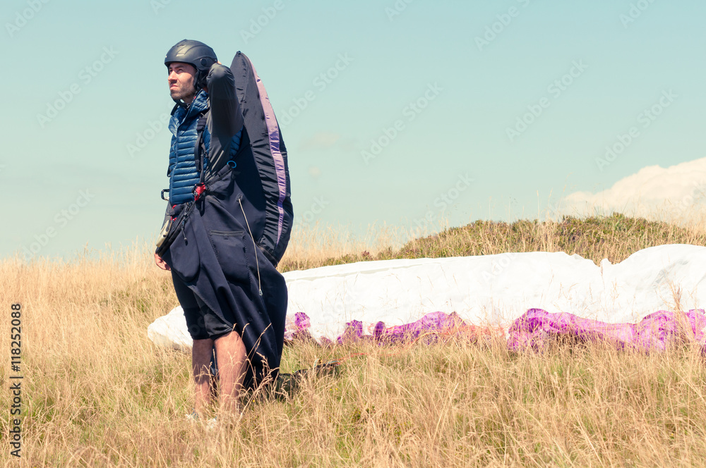 Male paraglider looking away waiting the wind