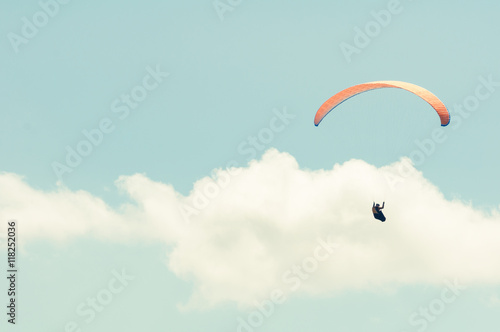 Paraglider in the blue cloudy sky