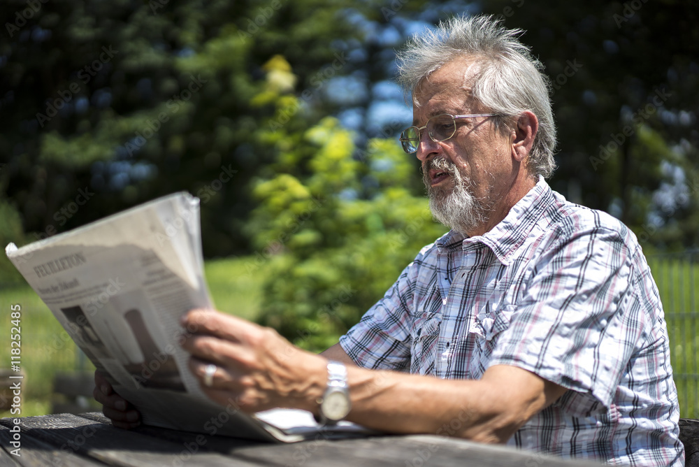Mann mit Bart und Brille liest in einer Tageszeitung Mann mit Bart und Brille liest in einer Tageszeitung