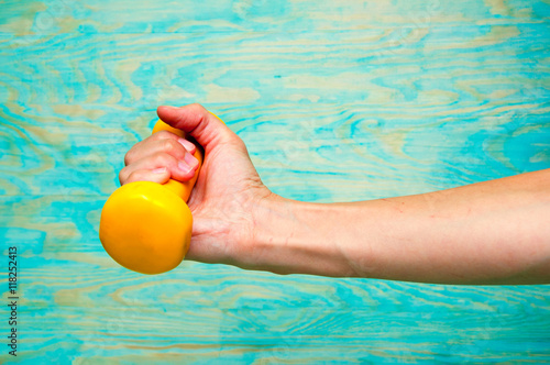 Girl holding yellow dumbbell on blue background