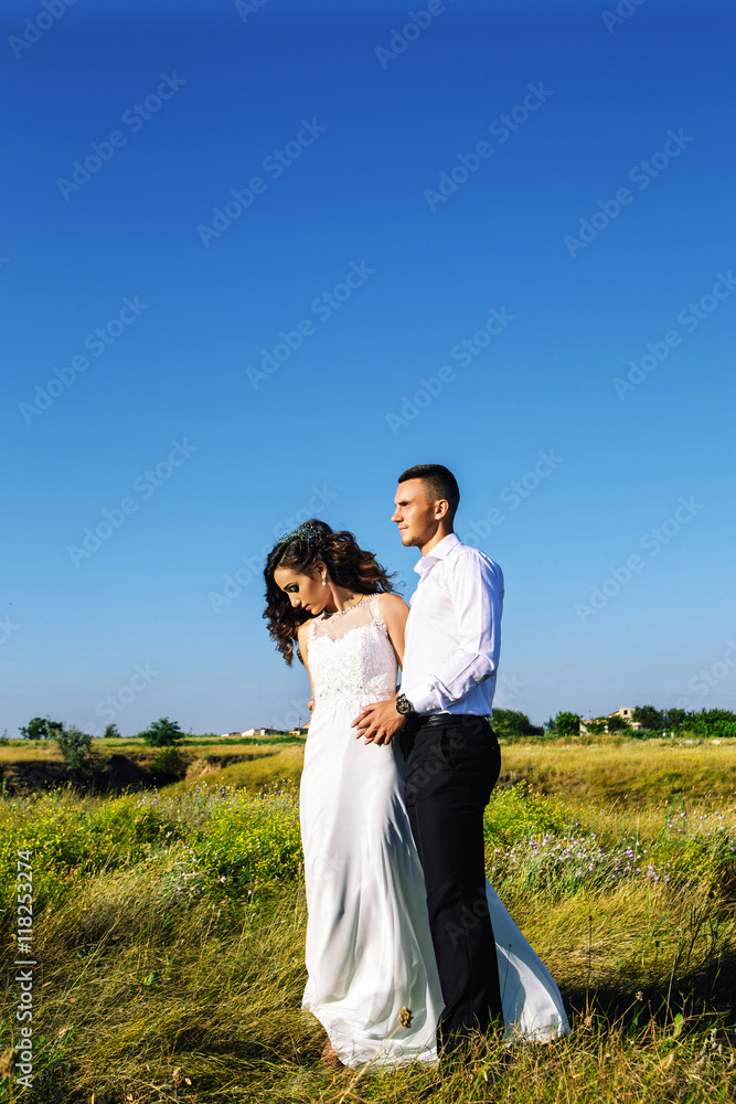 Beautiful couple in field, Lovers or newlywed posing on sunset with perfect sky Beautiful couple in field, Lovers or newlywed posing on sunset with perfect sky