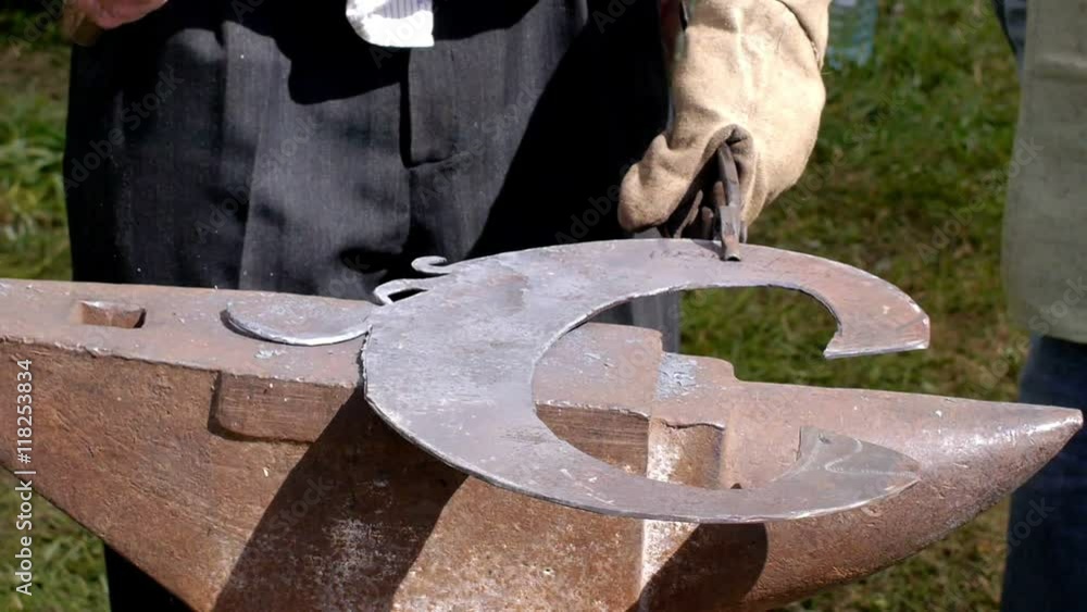 A blacksmith models a bar of iron with hammer after took it from fire forge. A blacksmith models a bar of iron with hammer after took it from fire forge.