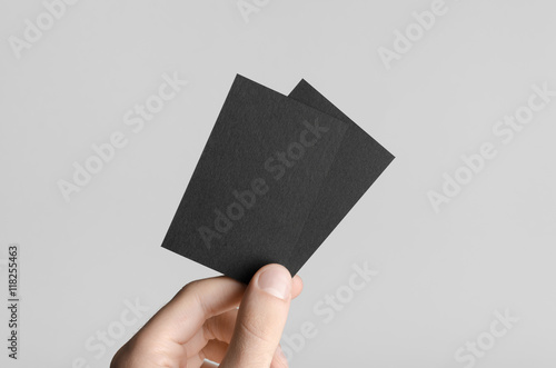 Black Business Card Mock-Up (85x55mm) - Male hands holding black cards on a gray background.