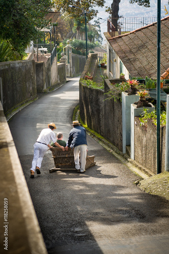 Fototapeta Downhill ride on cane sledges is popular touristic attraction of Funchal