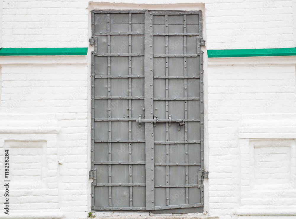 Large gray metal door on a white wall