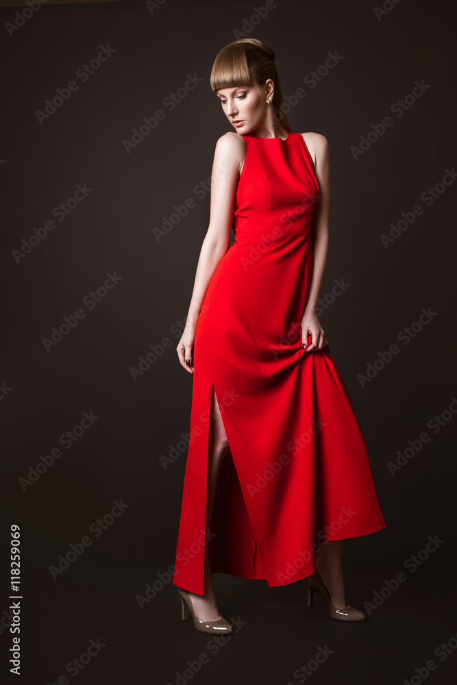 beautiful woman model posing in simple elegant red dress in the studio on black background
