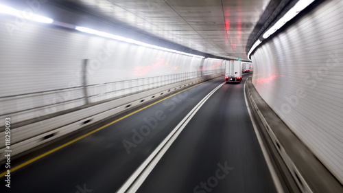 White lorry with red lights is driving into the tunnel.