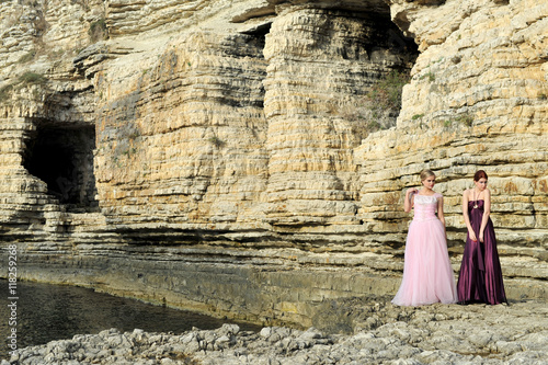 young fashion girls posing on the rocks with fashion dress