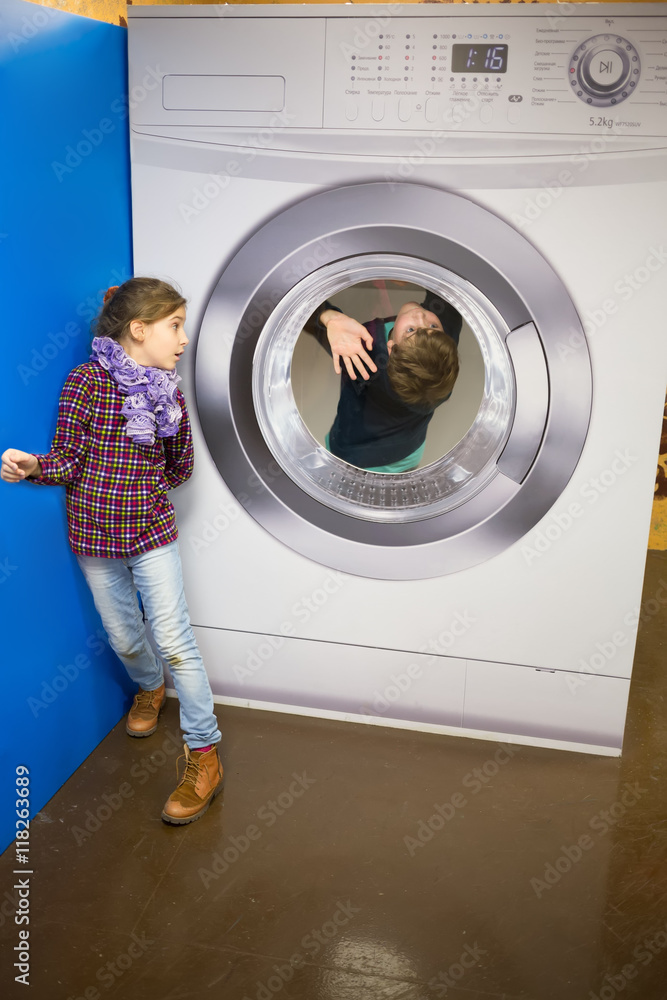 Two children are standing near large washing machine. Stock Photo | Adobe  Stock