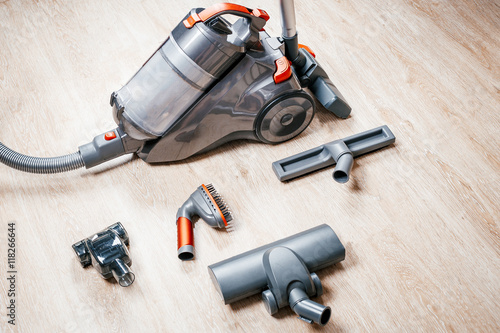 Hoover vacuum circuit with different nozzles stands on laminate floor at home