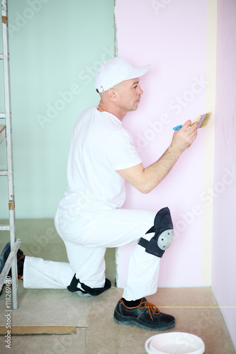 Finisher in white clothes painted walls in pink room © Pavel Losevsky