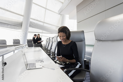 Businesswoman using cell phone in conference room photo
