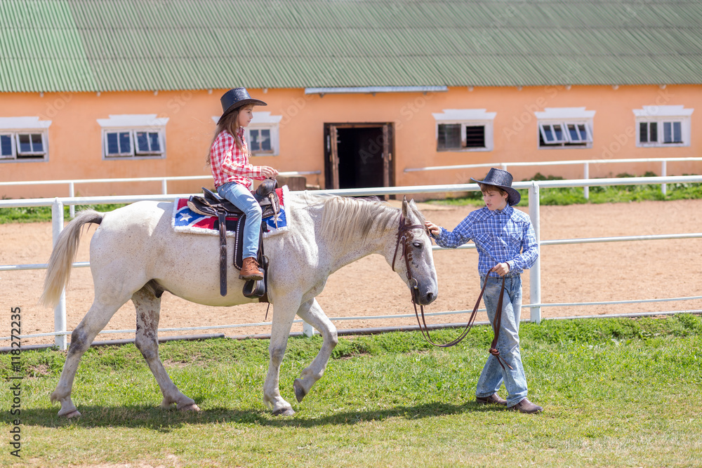cowboy brother leads the horse of his sister by the reins cowboy brother leads the horse of his sister by the reins