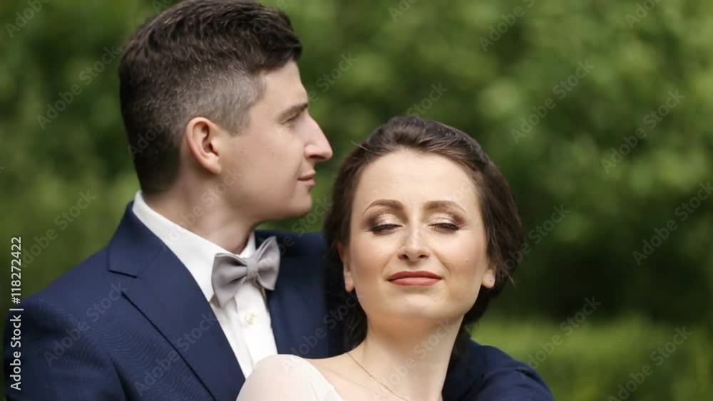 Beautiful happy young bride kissing handsome groom Beautiful happy young bride kissing handsome groom