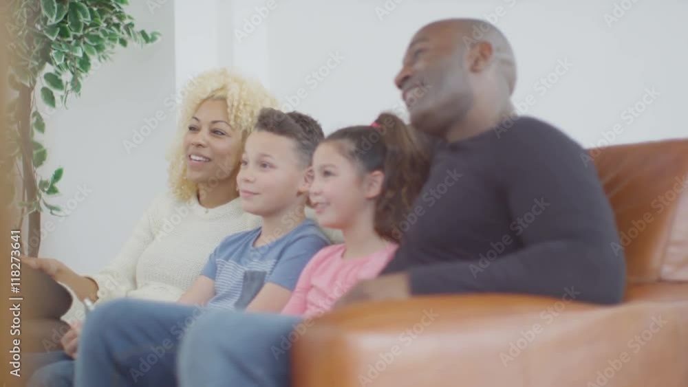 Happy laughing family watching TV on the couch at home Happy laughing family watching TV on the couch at home
