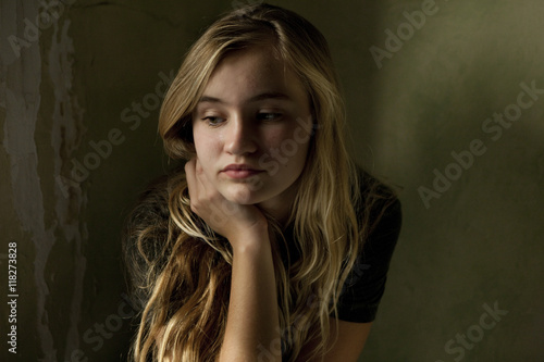 Serious teenage girl sitting by window