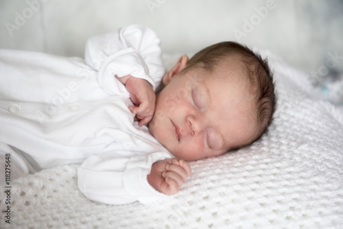Portrait image of a new born baby boy, laying on a white blanket. 