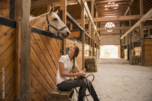 Caucasian girl sitting with horse in stable
