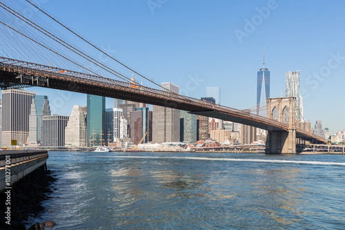 Cityscape of Brooklyn Bridge across East River and Manhattan at autumn sunny day.