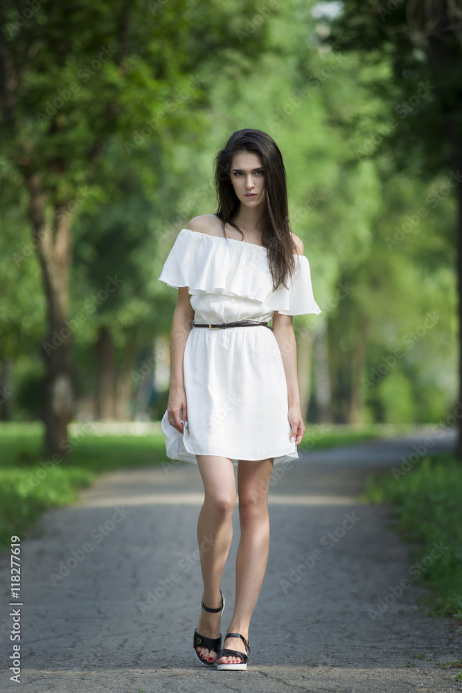 Full length portrait of a beautiful young caucasian woman in white dress with open shoulders, clean skin, long hair and casual makeup Full length portrait of a beautiful young caucasian woman in white dress with open shoulders, clean skin, long hair and casual makeup