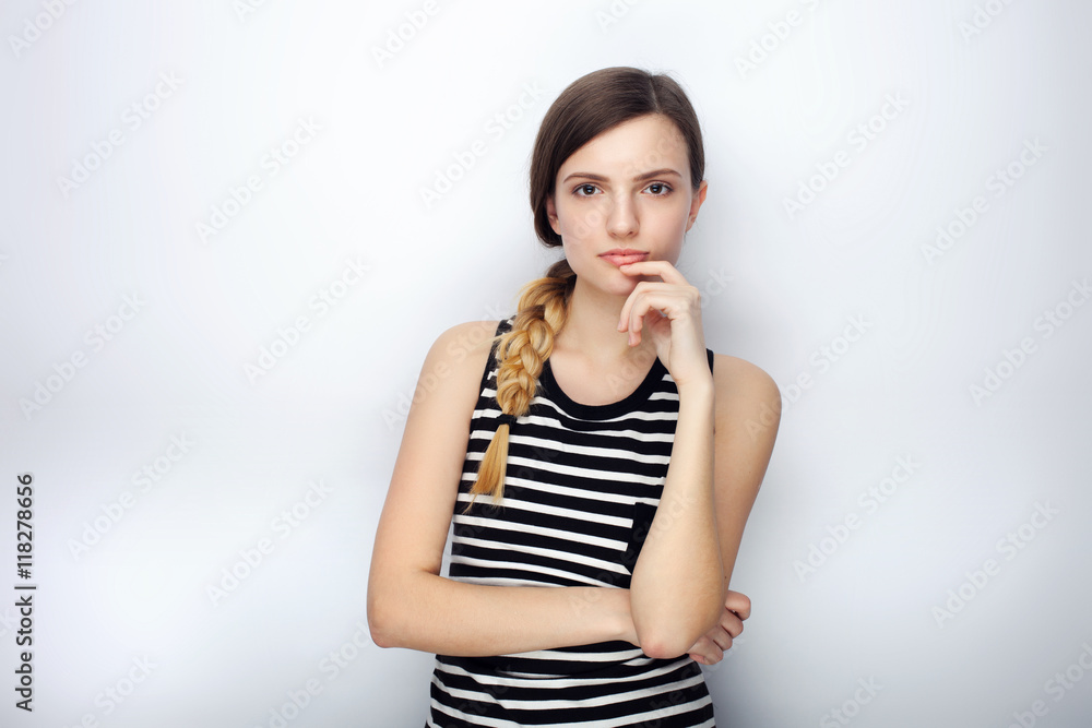 Portrait of serious young beautiful woman in striped shirt touching her chin posing for model tests against studio background Portrait of serious young beautiful woman in striped shirt touching her chin posing for model tests against studio background