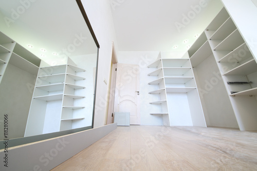 Installation of white corner sliding wardrobe and its reflection in mirror