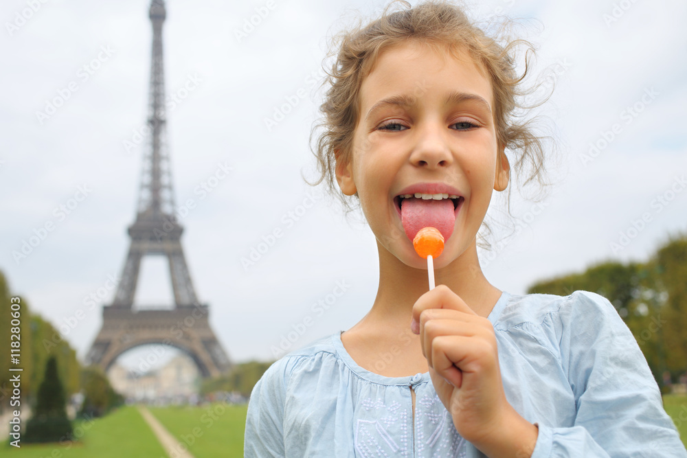 Portrait of a little girl licking a lollipop in front of the Eiffel Tower in Paris Portrait of a little girl licking a lollipop in front of the Eiffel Tower in Paris