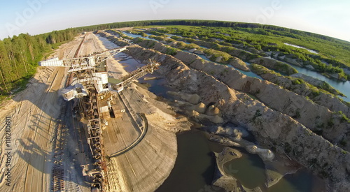 Big absetzer and railway at sandpit near forest during sunset. Aerial view. Photo with noise from action camera. photo