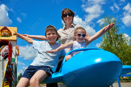 child and woman fly on blue airplane attraction in city park, happy family, summer vacation concept © soleg