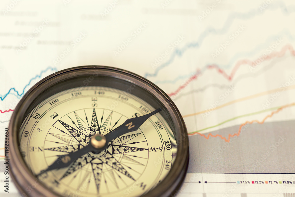 A compass on charts. A direction of successful investment A compass on charts. A direction of successful investment