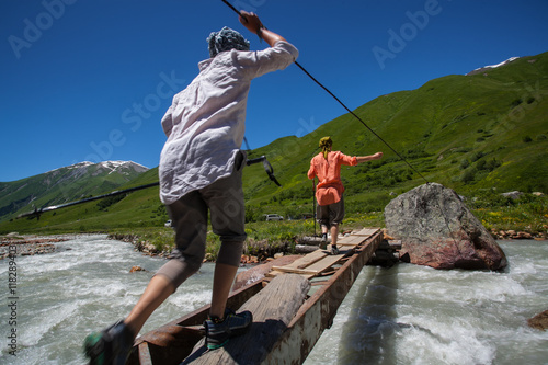 Tourists pass bridge across mountain river photo