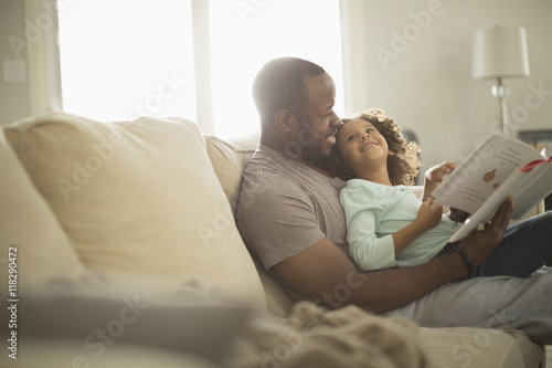 Father and daughter reading on sofa photo