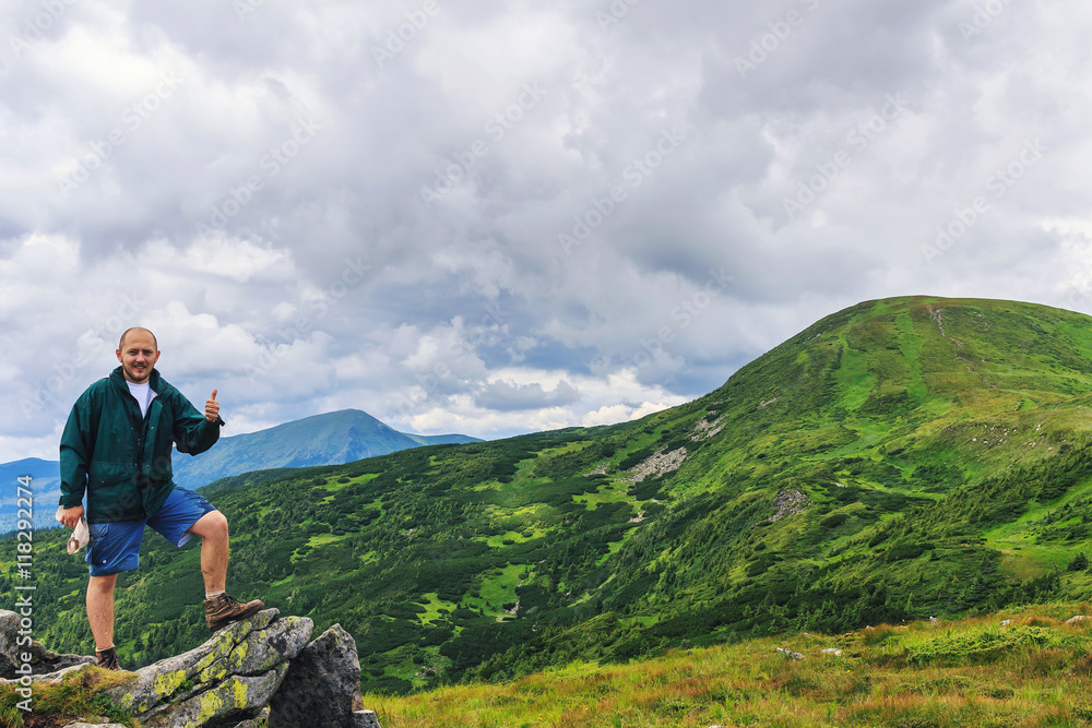 Portrait of young men tourist who standing on a rock and showing thumbs up, Carpathian mountains, summertime journey.