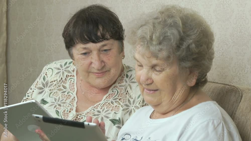 Two old women holding the silver digital tablets Two old women holding the silver digital tablets