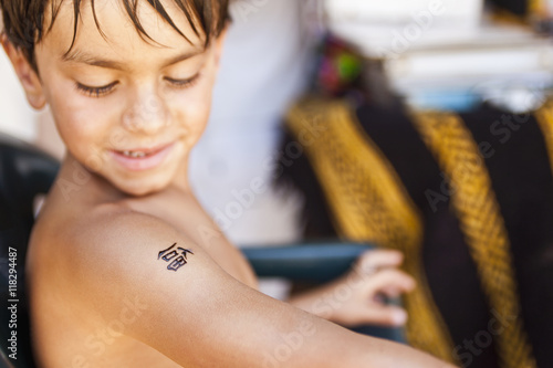 Mixed race boy looking at temporary tattoo photo