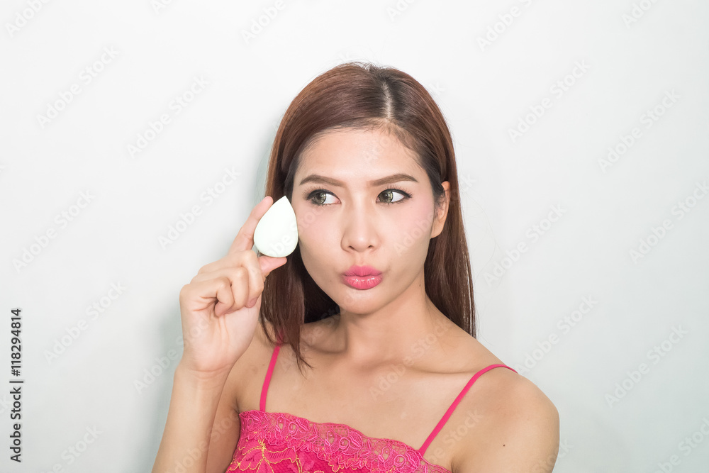 Beautiful young woman applying foundation to face with green egg Beautiful young woman applying foundation to face with green egg