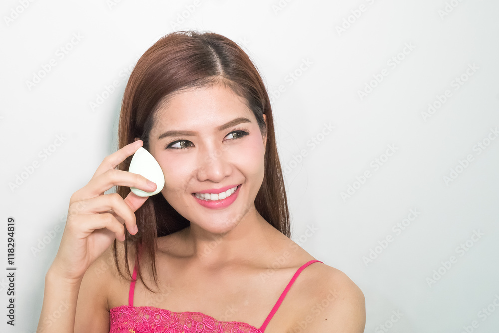 Beautiful young woman applying foundation to face with green egg Beautiful young woman applying foundation to face with green egg